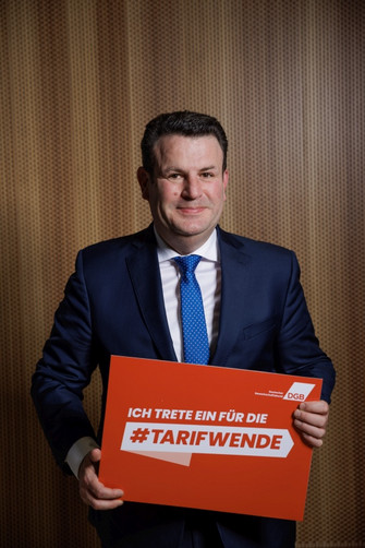 Hubertus Heil, der ein Plakat hält mit der Aufschrift "Ich trete für die Tarifwende"