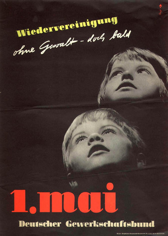 Maiplakat 1957: Text "Wiedervereinigung ohne Gewalt, doch bald. 1. Mai Deutscher Gewerkschaftsbund" Motiv: Zwei Kinderköpfe auf schwarzem Grund schauen nach oben.