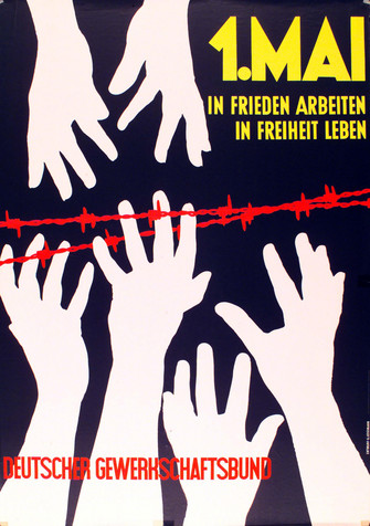 Mai-Plakat 1962:  Text_ "1. Mai. In Frieden arbeiten. In Freiheit leben. Deutscher Gewerkschaftsbund". Motiv: Zwei paar Gezeichnete weiße Hände strecken sich über einen Stacheldraht nach oben und ein Paar Hände kommt ihnen von oben entgegen.