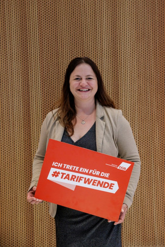 Portraitfoto von Kathrin Zellner, die ein Plakat in der Hand hält mit der Aufschrift "Ich trete ein für die #Tarifwende"