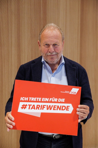 Foto von Frank Bsirske (Bündnis 90/Die Grünen), der ein Plakat hält mit der Aufschrift "Ich trete ein für die #Tarifwende"