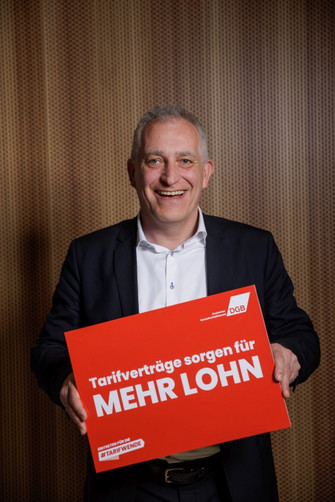 Portraitfoto von Jürgen Kerner, der ein Plakat hält mit der Aufschrift "Tarifverträge sorgen für mehr Lohn"