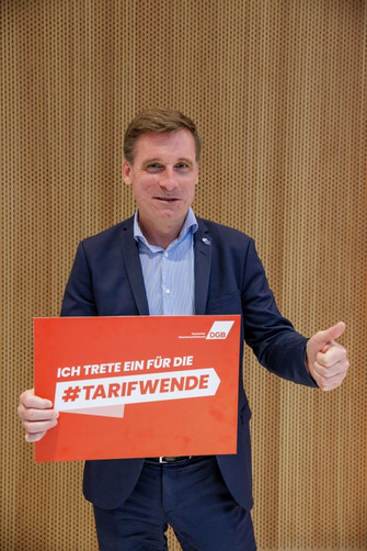 Foto von Oliver Röpke, Präsident des Europäischen Wirtschafts- und Sozialausschusses (EWSA), der ein Plakat in der Hand hält mit der Aufschrift "Ich trete ein für die #Tarifwende".