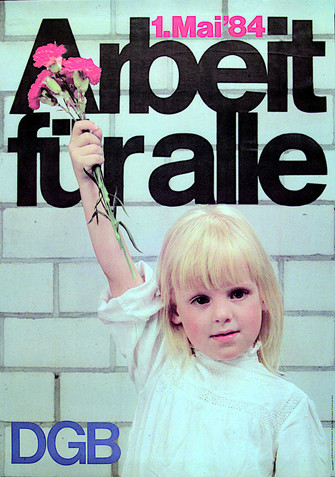 Maiplakat 1984. Text "1. Mai '84: Arbeit für alle". Motiiv: Ein kleines, blondes Mädchen in weißem Rollkragenpullover reckt den rechten Arm und hält einen Strauß mit drei Nelken in der Hand. Sei steht vor einer weißen Ziegelmauer.