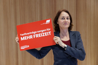 Portraitfoto von Katharina Barley (SPD), die ein Plakat in der Hand hält mit der Aufschrift "Tarifverträge sorgen für mehr Freizeit". 