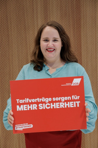 Foto von Ricarda Lang (Bündnis 90/Die Grünen), die ein Schild hält mit der Aufschrift "Tarifverträge sorgen für mehr Sicherheit"